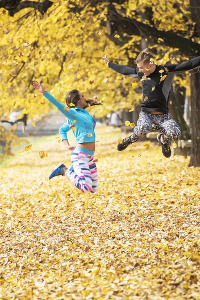 Schönes junges Paar feiert und springt nach erfolgreichem Training im Park. Herbstliches Umfeld. — Stockfoto