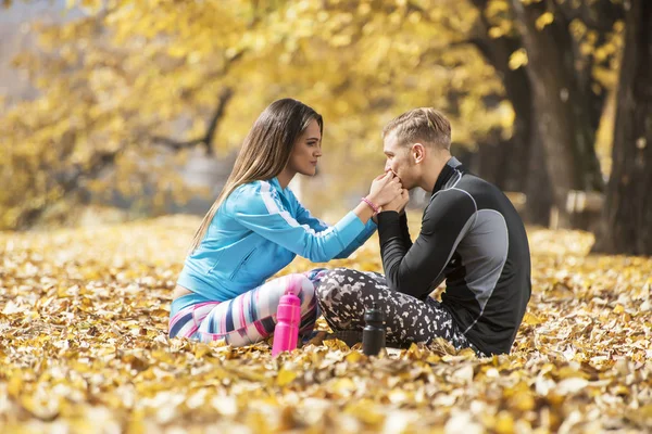 Красивая молодая пара отдыхает и целуется после успешной тренировки в парке. Осенняя среда . — стоковое фото