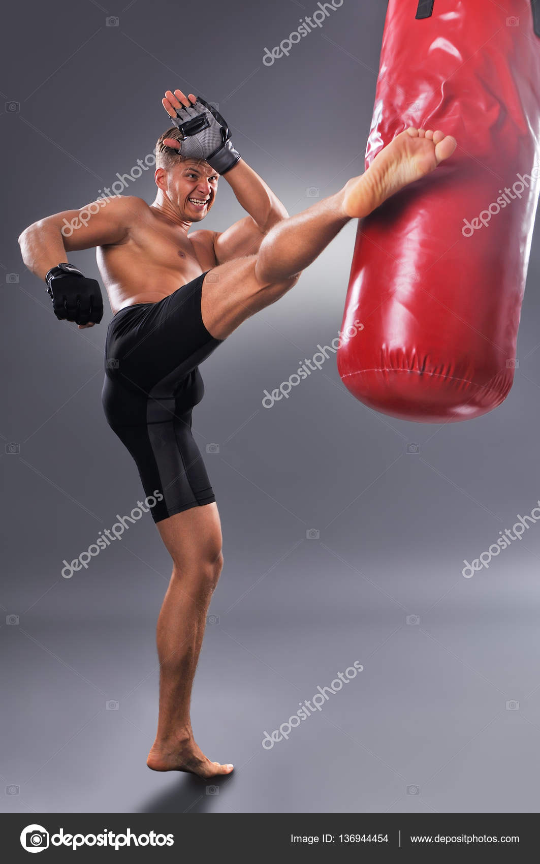 Muscular combate practicando algunas patadas con el saco de boxeo en