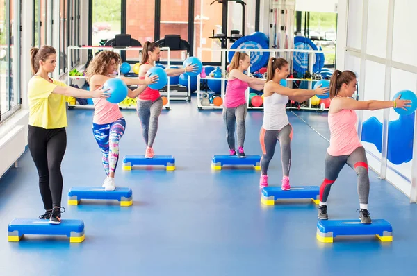 Group of beautiful young women working out on blue stepper and smiling. — Stock Photo, Image