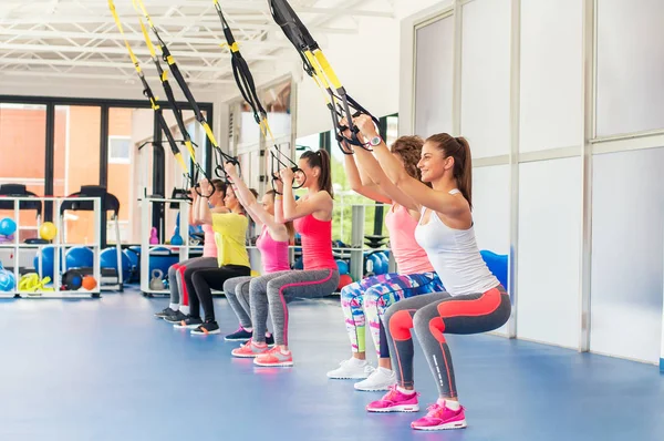 Group of beautiful young women working out on TRX and smiling. — Stock Photo, Image