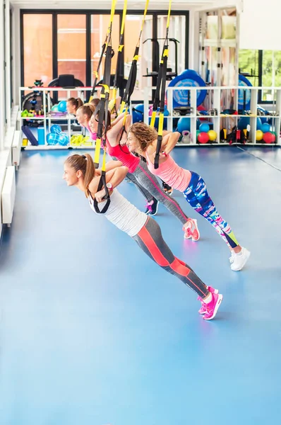 Group of beautiful young women working out on TRX and smiling. — Stock Photo, Image