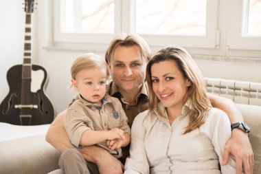 Mutlu anne onların güzel bebek çocuk ile kanepede oturan portresi. Aile değerleri.