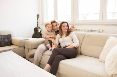 Güzel bebek oğulları ile kanepede oturan mutlu anne. Parmak işaret. Aile değerleri.