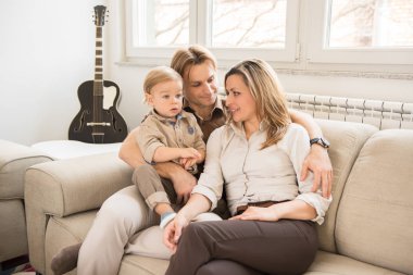 Mutlu anne onların güzel bebek çocuk ile kanepede oturan portresi. Aile değerleri.