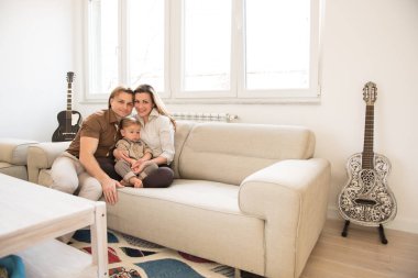 Güzel bebek oğulları ile kanepede oturan mutlu anne. Aile değerleri.