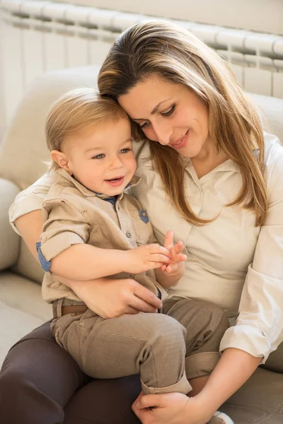 美しい母と幼い息子の膝の上に座っての肖像画。家族の価値観. — ストック写真