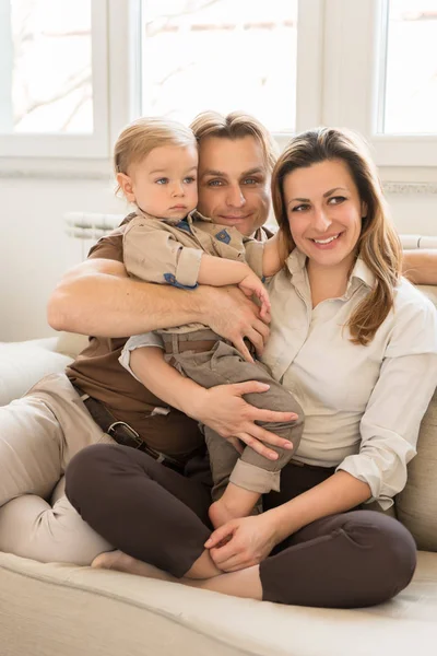 Ritratto di genitori felici seduti sul divano con il loro bellissimo bambino. Valori familiari . — Foto Stock