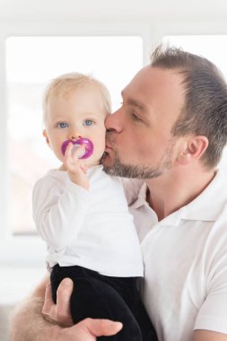 Mutlu baba kızını öperken portresi. Aile değerleri. Boş zaman birlikte. Emzik ağzında ile kız bebek.