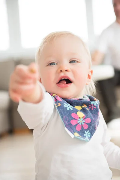 Portrait of nicely dressed and happy baby girl pointing with finger. — Stock Photo, Image