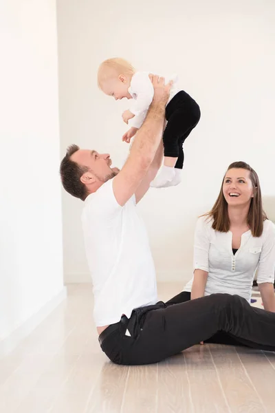 Heureuse famille de trois personnes profite à la maison. Les parents et leur belle petite fille assise sur le sol et jouant. Père élever sa fille. Les valeurs familiales. Loisirs ensemble . — Photo