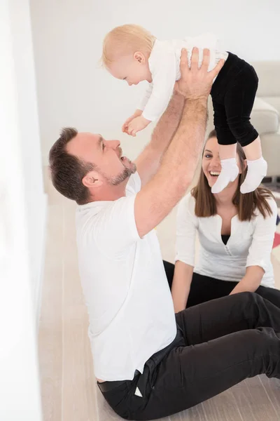 Heureuse famille de trois personnes profite à la maison. Les parents et leur belle petite fille assise sur le sol et jouant. Père élever sa fille. Les valeurs familiales. Loisirs ensemble . — Photo