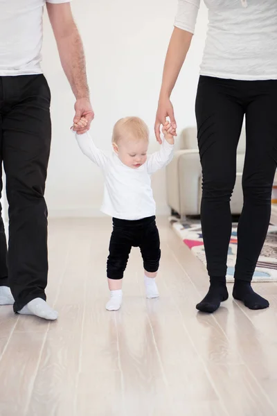 Heureuse famille de trois personnes appréciant à la maison. Les parents apprennent à marcher à leur belle petite fille. Les valeurs familiales. Loisirs ensemble . — Photo