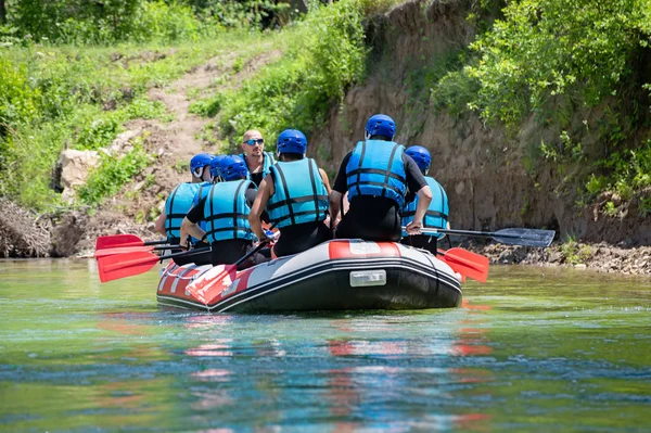Rafting team goes down the river on the beautiful sunny day. Back view. — Stock Photo, Image