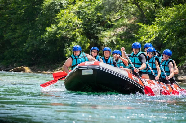 Rafting team goes down the river on the beautiful sunny day.