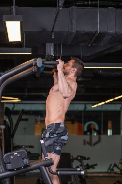 Kaslı seksi genç adam yatay çizginin arkasında egzersiz yapıyor. Yan görünüm