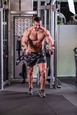 Kablo makinesinde göğüs için kelebek egzersizi yapan seksi kaslı adam.