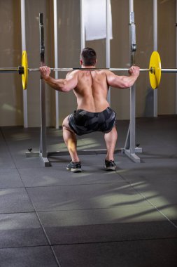 Seksi kaslı adam çömelme egzersizi yapıyor. Arka plan
