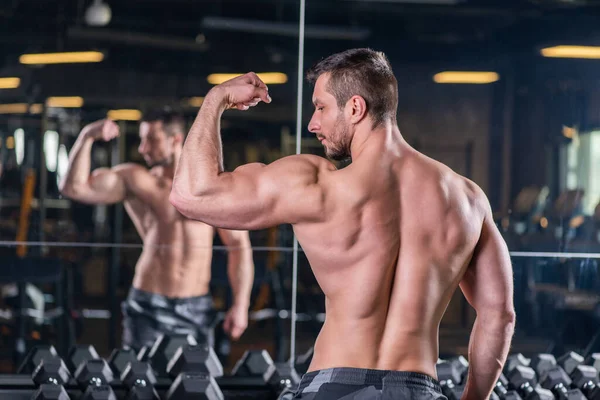 年轻性感的肌肉男在镜子前摆出二头肌收缩的姿势 — 图库照片