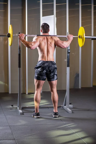 근육질의 남자가 앉아서 운동을 합니다 뒷모습 — 스톡 사진
