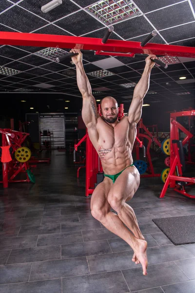 強力な筋肉の男が横棒で腹筋運動をする — ストック写真
