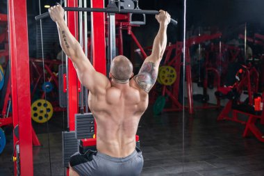 Güçlü kaslı adam, Lat makinesinde egzersiz yapıyor.