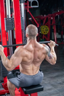 Güçlü kaslı adam, Lat makinesinde egzersiz yapıyor.