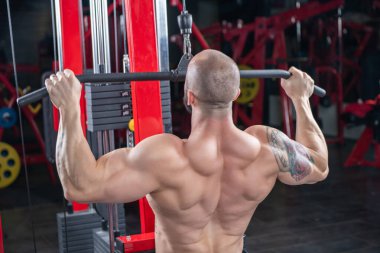 Güçlü, kaslı bir adamın arka tarafta egzersiz yapmasına yakın.