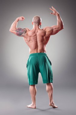 Gri arka planda poz veren seksi kaslı vücut bulucu. Arka plan