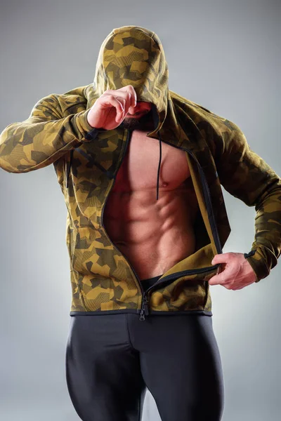 Sexy Gespierde Bodybuider Poseren Met Sweatshirt Kap Grijze Achtergrond — Stockfoto