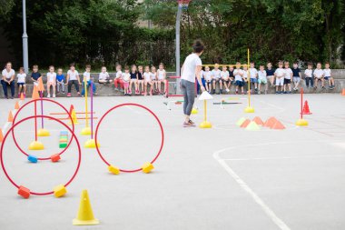 Merdivenlerde oturup antrenörlerin pratik performansını izleyen bir grup çocuk. Spor okulu