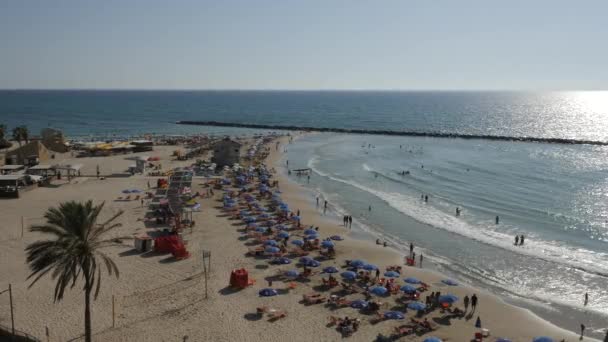 Tel Avivビーチで人々とアクティブな晴れた日混雑したビーチで日光浴を人々 波が海岸に圧延 日当たりの良い夏 — ストック動画