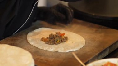 Şef mutfakta Meksika Burito 'su pişiriyor. Etli tortilla eti sarıyor. Meksika dürümü pişiriyorum. Garson elleri tortilla doldurarak burrito paketliyor. Gurme