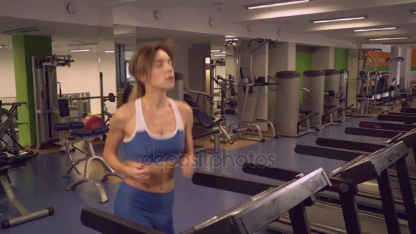 Взрослая женщина бегает на кардио-автоматах в спортзале . — стоковое видео