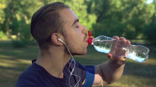 Um homem está bebendo água após o treino na floresta . — Vídeo de Stock