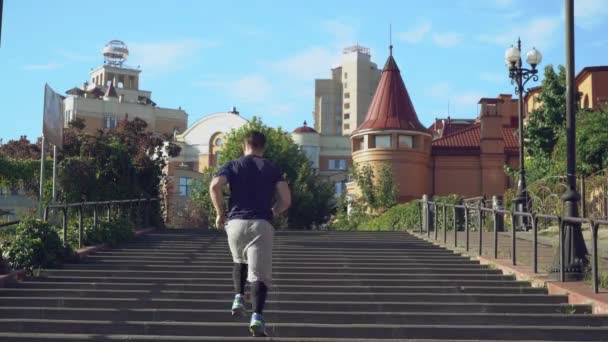 Un deportista está subiendo las escaleras y salta para saludar su logro en la parte superior . — Vídeos de Stock