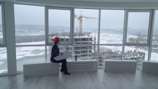 Człowiek patrząc na budowie przez okno. — Wideo stockowe