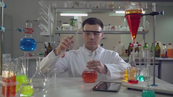 Schöner professioneller Wissenschaftler mit Fläschchen im Labor — Stockvideo