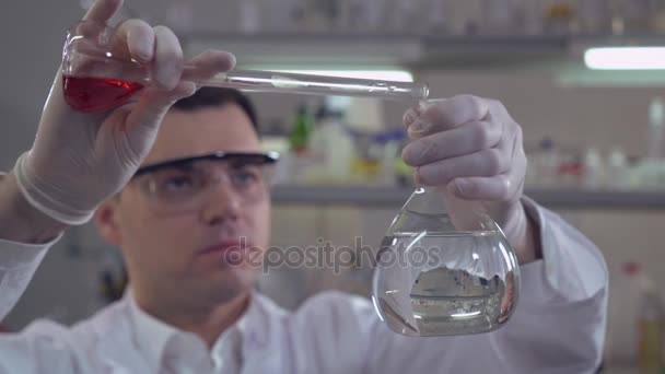 Homme ajoutant du liquide à une ampoule en verre . — Video