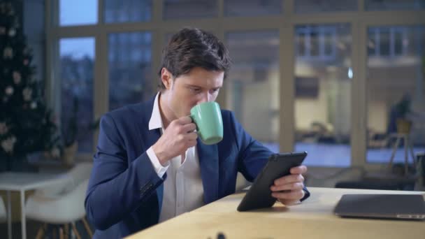 Joven hombre de negocios leyendo revista en línea en interiores — Vídeos de Stock