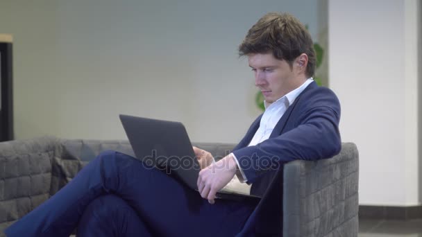Jovem masculino relaxante no lobby uso pc — Vídeo de Stock