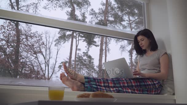 Girl working with computer on windowsill. — Stock Video