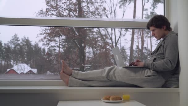 Man sitting on the window sill use laptop — Stock Video