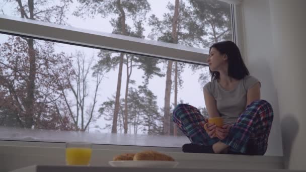 Menina sentada no peitoril da janela pela manhã . — Vídeo de Stock