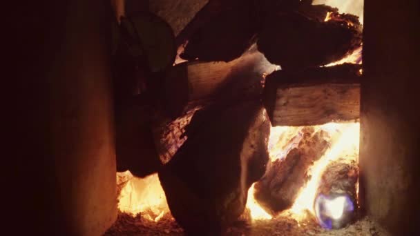 A large pile of firewood, burning in a brick fireplace, the flames of flame burst up, real firewood, very warm. — Stock Video