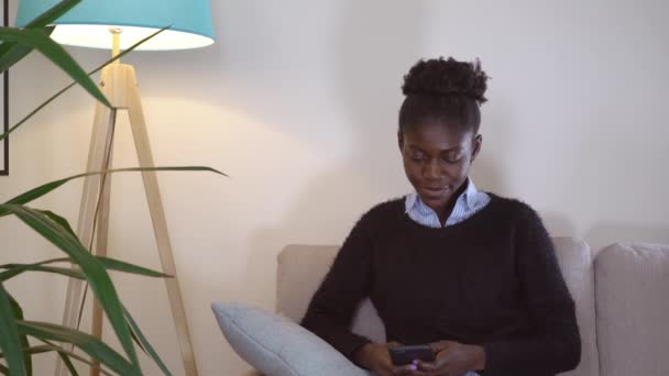 Afrikansk flicka SMS meddelande hemma. — Stockvideo