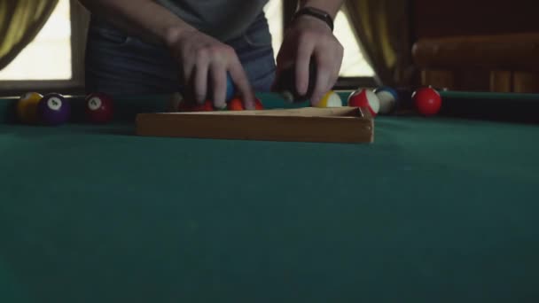 Un homme met des balles dans un triangle pour un billard américain, fait une pyramide . — Video