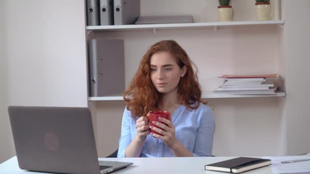 Gengibre menina beber chá no trabalho . — Vídeo de Stock