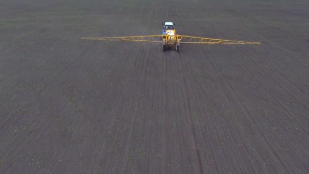 Трактор їде по полю, обприскуючи врожай, стріляючи з повітря . — стокове відео