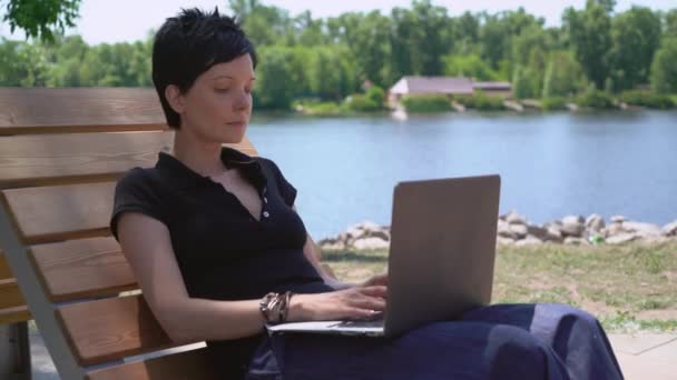 Žena pracuje na notebooku venku. — Stock video